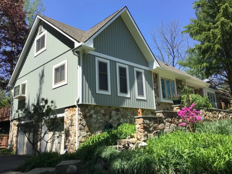 new green siding on a rock with stone accents surrounded by a garden