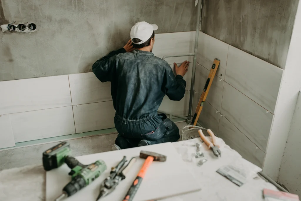 Contractor installs shower tiles in a bathroom